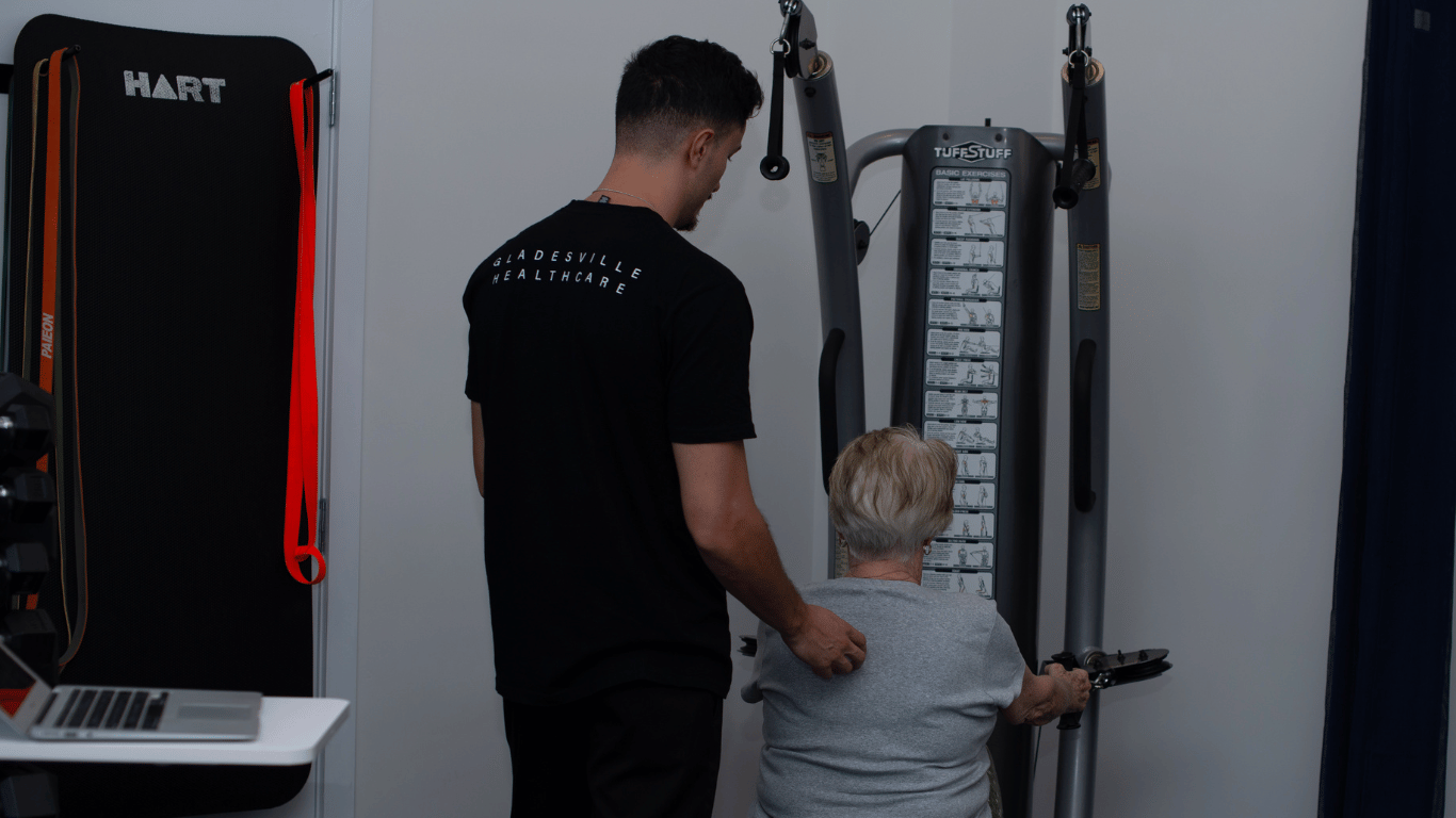 Male exercise physiologist instructing a female client on a weights machine