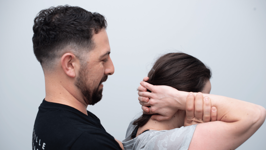 Female patient with hands behind her head and Gladesville Healthcare chiropractor treating neck pain and muscle tension