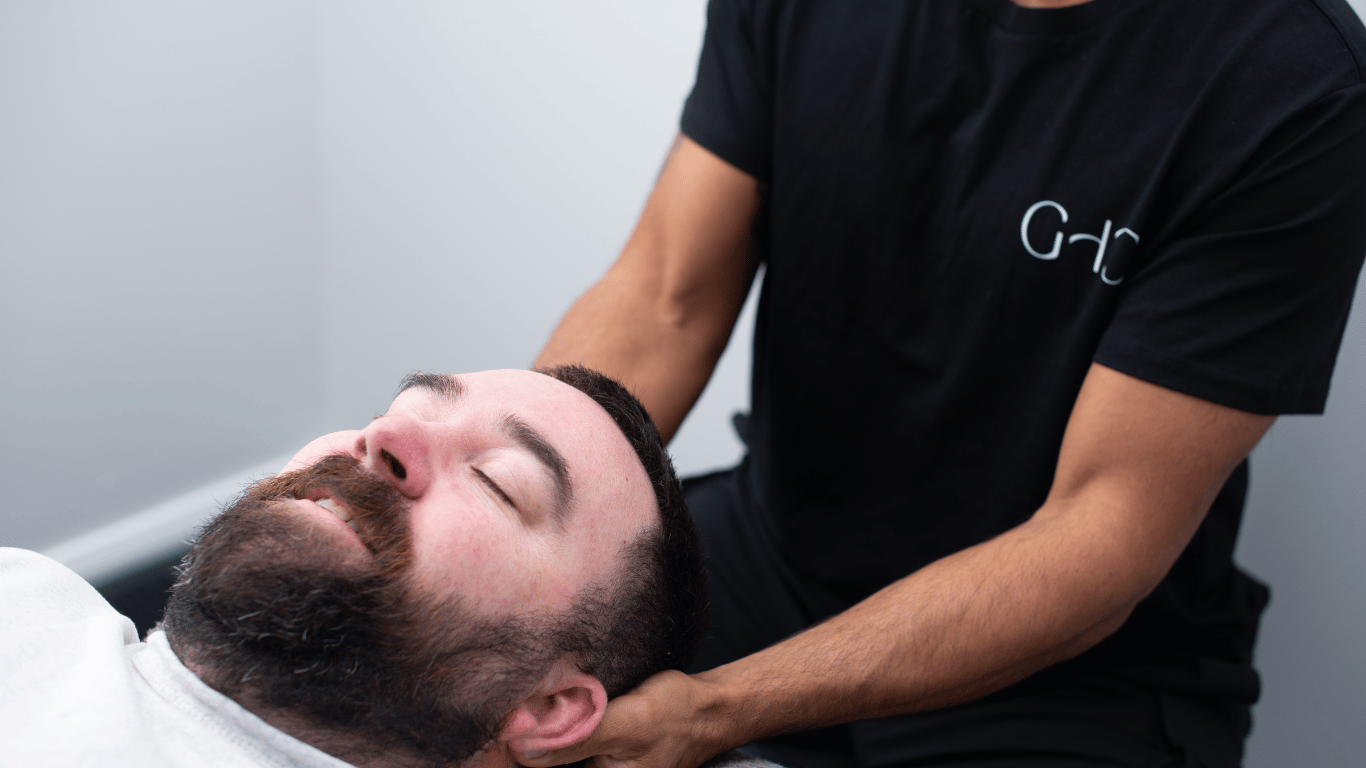 Male patient lying down with a Gladesville Healthcare therapist treating neck pain