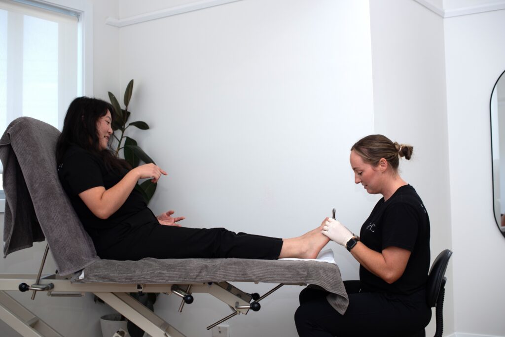 A podiatrist examines a patient's foot in a clinical setting.